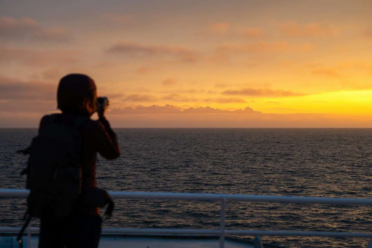 Man taking a photo of the sunset in a boat